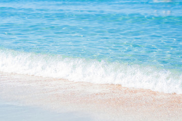Soft sea waves wash over golden sand in a beach. Blured natural background