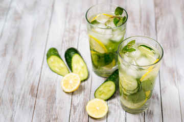 Water with lemon, mint and cucumber on wooden light background. Water Detox.