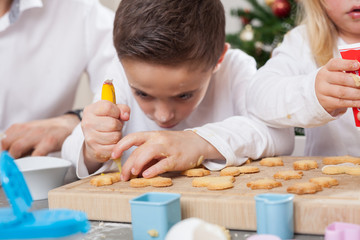 Obraz na płótnie Canvas childs using sugar font to decorate christmas cookies