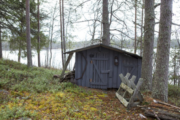 Old shed for tools by the lake. An old saw is hanging on the wall.