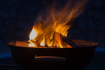 Firewood burning in grill bowl at night