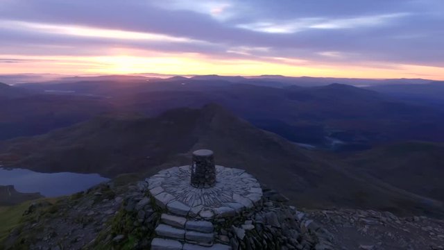 Low aerial orbit of the summit of Mount Snowdon at sunrise.