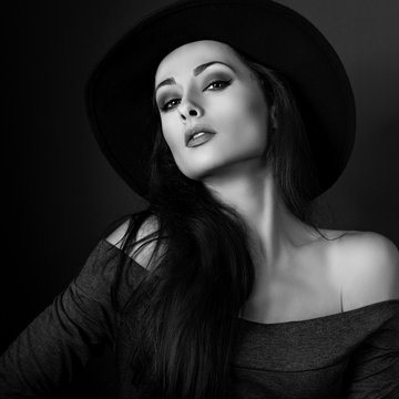 Sexy elegant makeup woman in fashion hat posing on dark shadow b