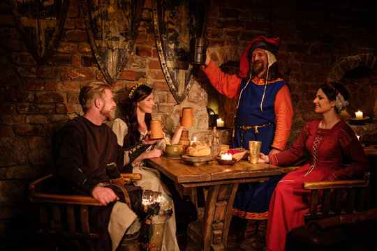 Medieval people eat and drink in ancient castle tavern