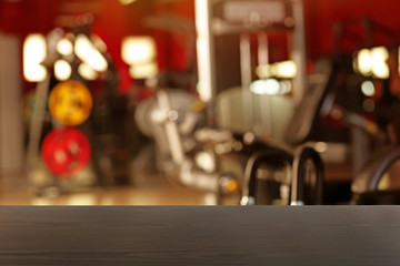 Wooden table against blurred gym interior background. Sport and healthcare concept.