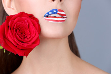 Naklejka premium Girl with USA makeup and red rose on grey background