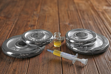Weight disks and syringe on wooden background