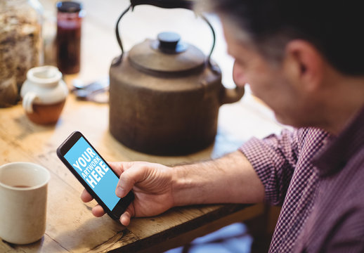 User with Smartphone at Wooden Table with Kettle Mockup