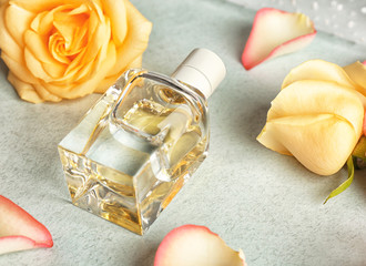 Composition of perfume bottle and roses on light background
