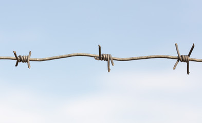 Barbed wire on a wooden post against blue sky