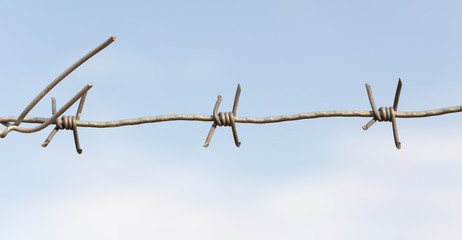 Barbed wire on a wooden post against blue sky