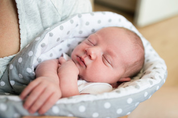 Unrecognizable mother holding newborn baby son in her arms