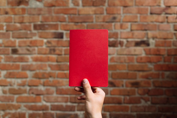 Hand holding red notebook on the brick background - Mock up