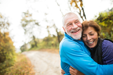 Beautiful senior couple running outside in sunny autumn forest