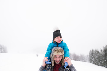Fototapeta na wymiar Father giving his son piggyback. Winter nature.