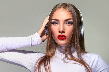 Girl with big headphones listening to music.
Brown haired woman with long straight hair with red lips in white clothes.