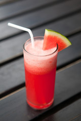 Glass of watermelon smoothie on a wooden table. Selective focus