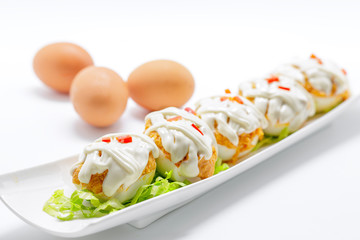 Stuffed eggs with tuna, tomato, mayonnaise and red pepper on whi