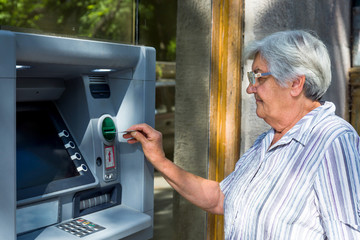 elderly woman inserting credit card to ATM
