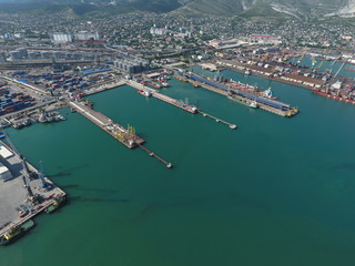 Fototapeta premium Industrial seaport, top view. Port cranes and cargo ships and barges. Loading and shipment of cargo at the port. View of the sea cargo port with a bird's eye view
