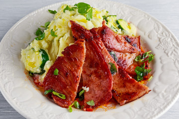 Sliced Gammon Steak with mashed potato on wooden white background.