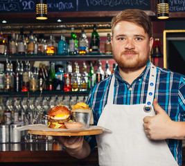 Chef in apron presenting a tray with burger