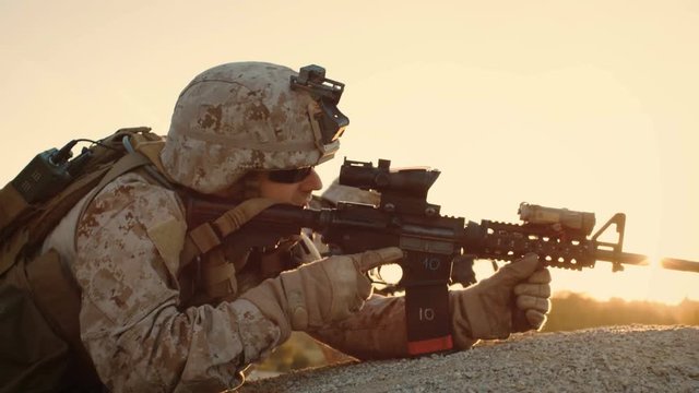 Side view Soldiers Lie Down on the Hill, Aim through the Assault Rifle Scope in Desert Environment in Sunset Light. Slow Motion.