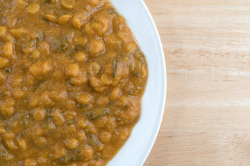 Spinach and lentils on a plate atop a wood table.