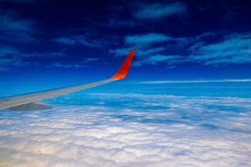 Fototapeta na wymiar Plane Wing on Cloudscape background