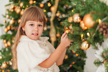 the girl at the Christmas tree holding Christmas decoration
