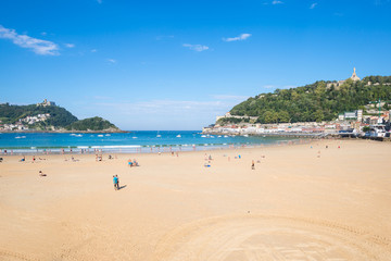 Fototapeta na wymiar The Beach of La Concha Donostia, a sand beach with shallow waters and tide. It is one of the most famous urban beaches in Europe. Donostia San Sebastian is European Capital of Culture 2016