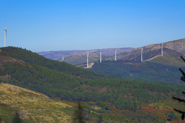 Electric generators located in countryside with beautiful landscape on background, wind turbines against cloudy sky and sun rays, alternative energy resources