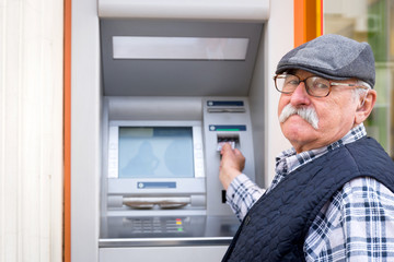 old man inserting credit card to ATM