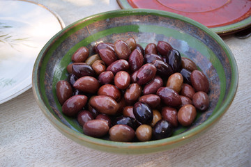 Black and brown olives in a green terracotta bowl