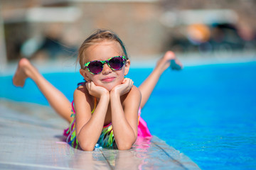 Little happy girl in outdoor swimming pool enjoy her vacation