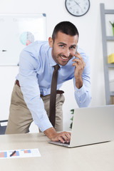 Younf business man in his office talking  on the cell phone