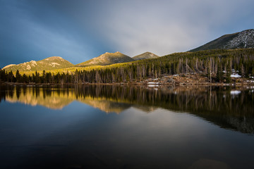 Fototapeta na wymiar Mountains and trees reflected in a calm lake.