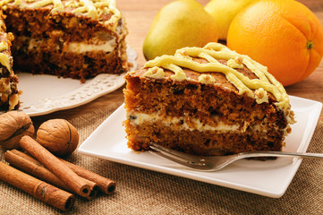 Pumpkin cake with cream and fruits on wooden background.