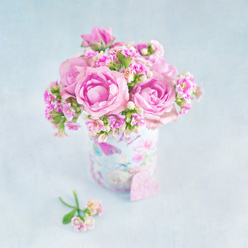 Lovely bunch of a pink flowers in a vase ,decorated with a heart on a table .