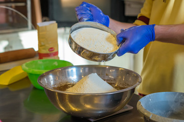 Hands Sift flour in a bowl. Preparing cakes