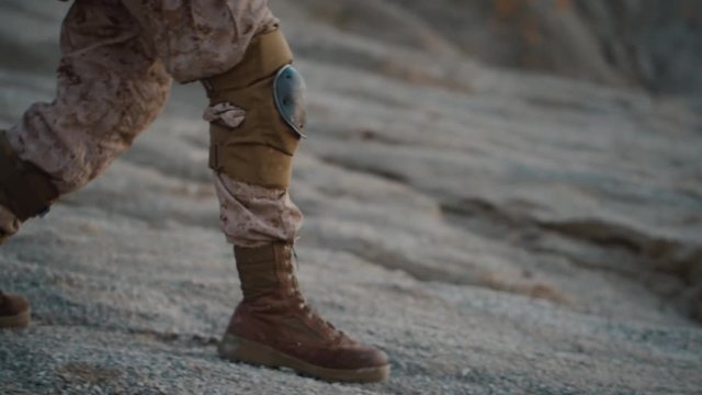 Close-up shot of Walking Soldier's Legs in Desert Environment. Slow Motion.