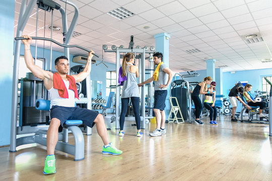 Small group of sportive friends at gym fitness club center - Happy sporty people interacting in weight room training - Social gathering concept in sport lifestyle context - Main focus in middle frame