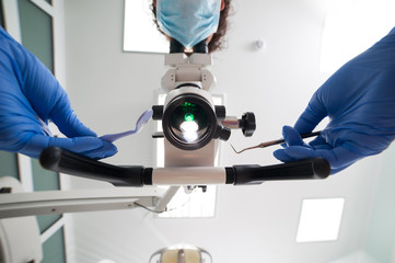 Image of a dentist who is using the dental microscope in the cli