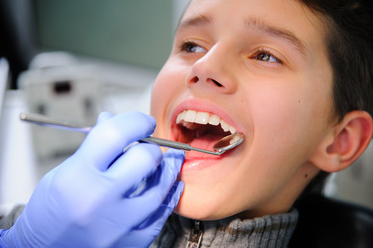 Photo of little boy having mouth checkup in dental clinic