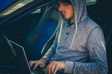 hacker sit in car with his laptop