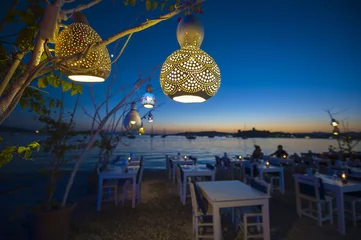 Gordijnen Informal beachside seating with decorative gourd lights hanging from a tree in Bodrum, Turkey © lazyllama