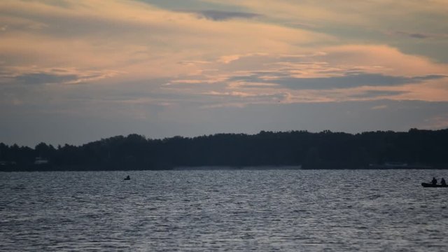 Silhouette of two persons in motor boat at dawn on river or lake, probably fishermen