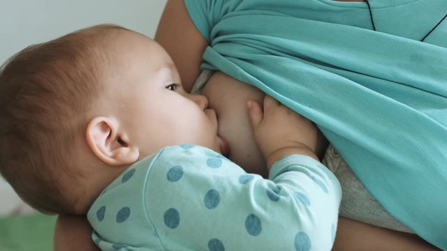 Mother feeds her baby breast milk and lulls baby