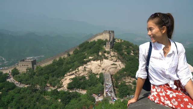 Great Wall of China. Tourist on Asia travel looking at Chinese landscape sitting relaxing on famous Chinese tourist destination and attraction in Badaling north of Beijing. Woman traveler on vacation.