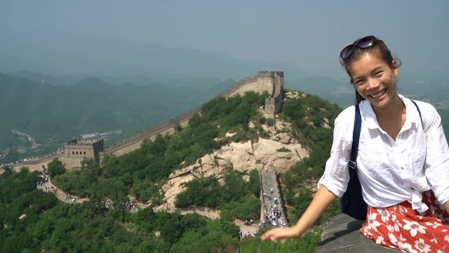 Great Wall of China. Tourist on travel waving hand saying hello to camera by famous Chinese tourist destination and attraction in Badaling north of Beijing. Woman traveler on vacation.